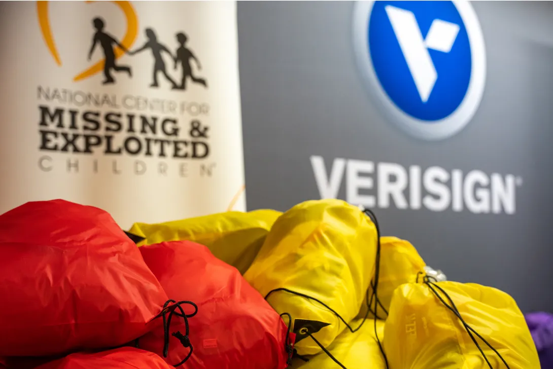 Red and yellow backpacks full of supplies set down under a Verisign and National Center for Missing and Exploited Children logos.