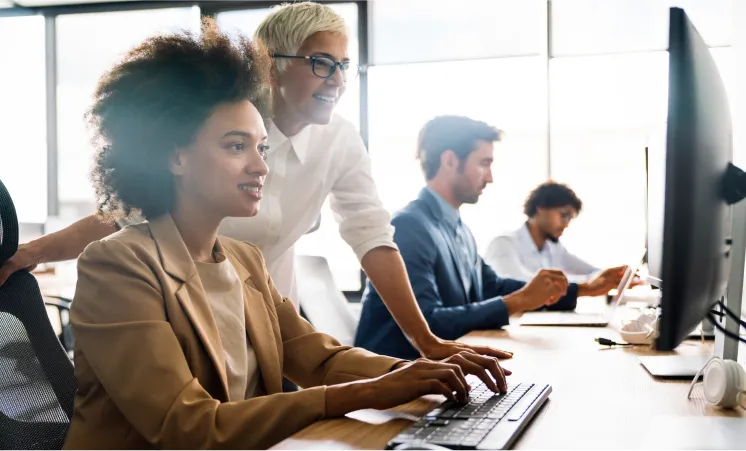 Professional colleagues brainstorming ideas and working together in front of a computer in an open office.