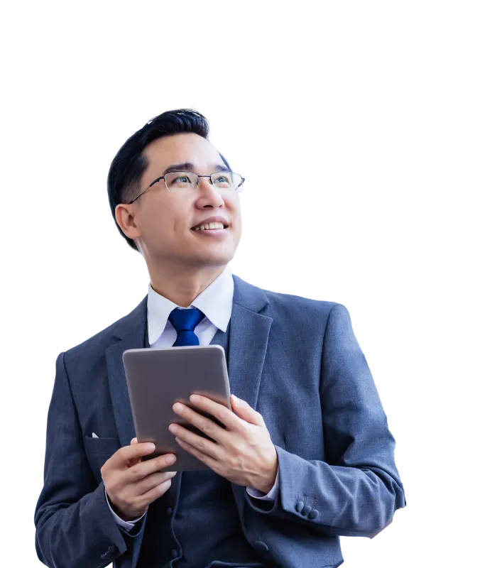 A smiling and confident businessman wearing a suit and holding a digital tablet in his hands while looking out into the distance.